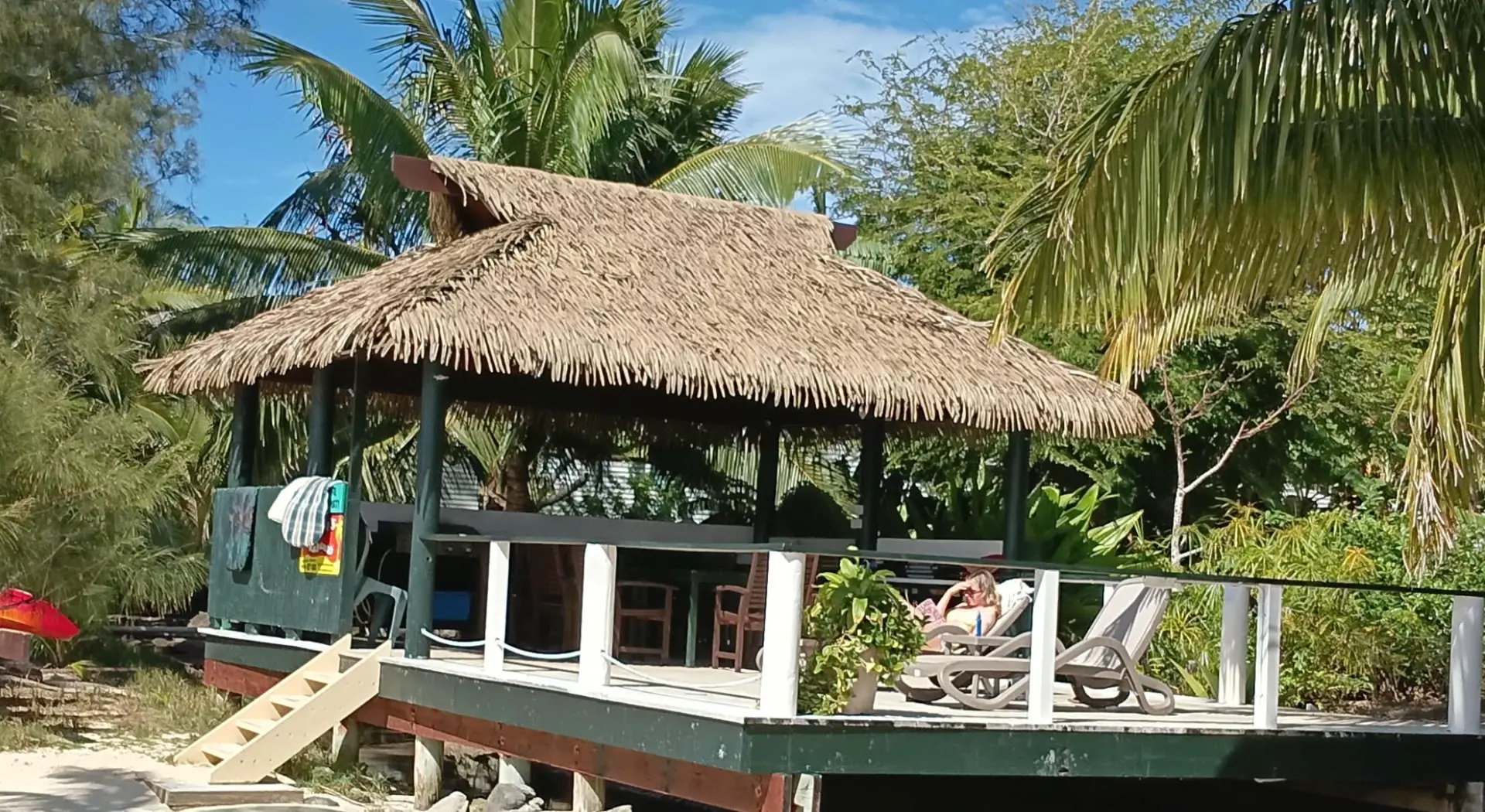 Open-air thatched-roof gazebo built on a raised deck by the beach